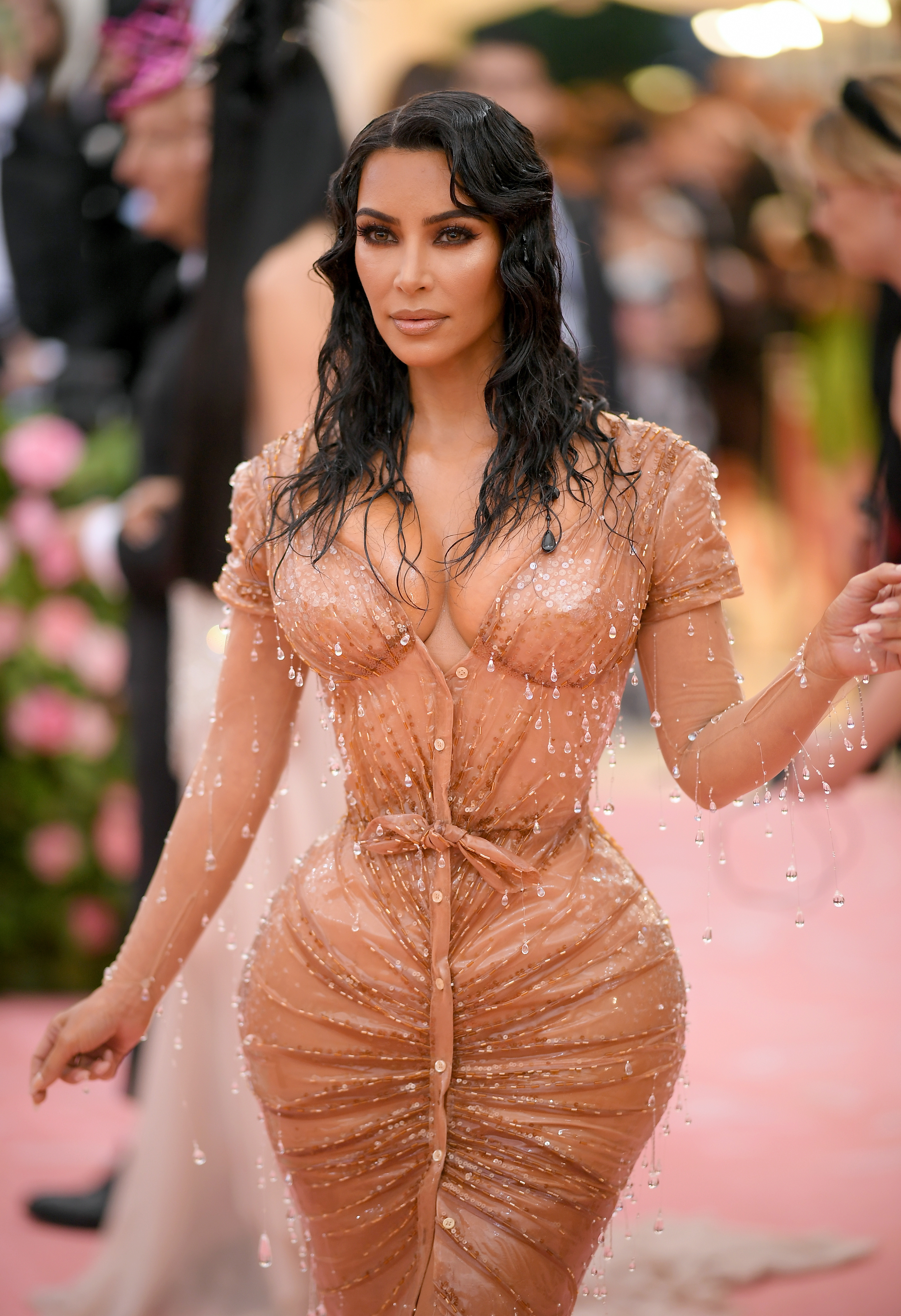 Kim Kardashian in a fitted, bejeweled dress with a wet-look effect at a formal event