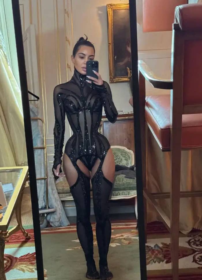 Kim Kardashian in a sheer, form-fitting outfit taking a mirror selfie