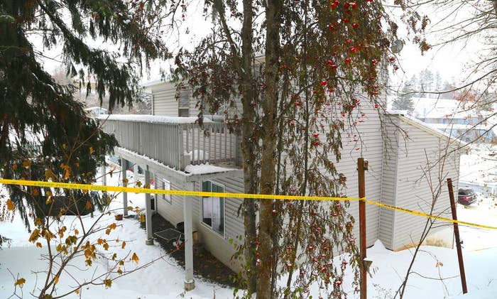 Snow-covered house with caution tape in front, suggesting a restricted or investigation scene in a snowy setting