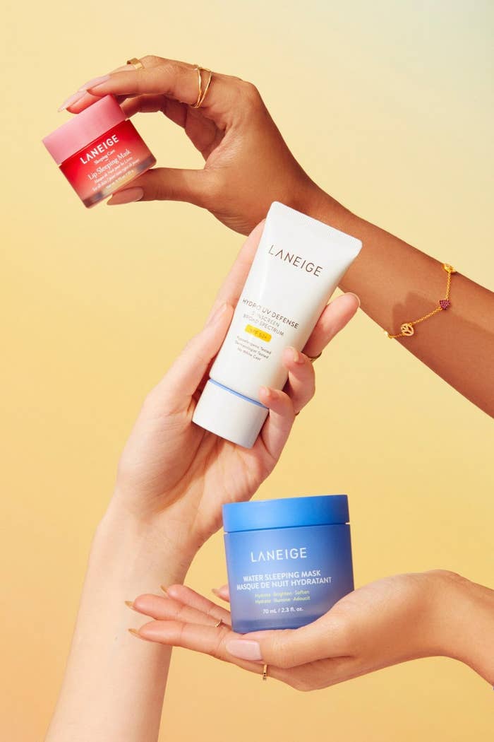 Tres manos sostienen productos de cuidado facial Laneige, incluyendo una crema, un gel y una mascarilla, en un anuncio publicitario