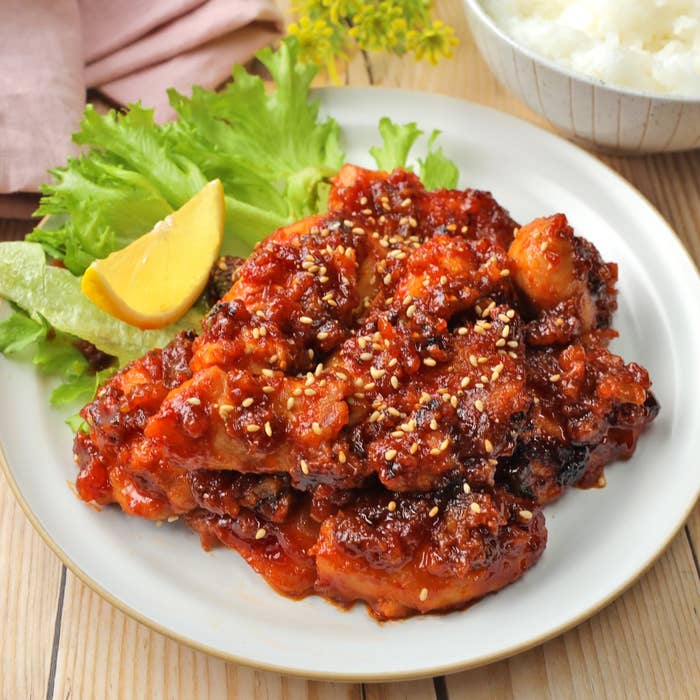 レタス、レモン、ゴマを添えた韓国風フライドチキンの皿。白ご飯も後ろに写っています。