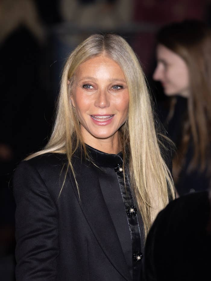 Gwyneth Paltrow in a sleek, tailored suit with long straight hair, smiling at an event
