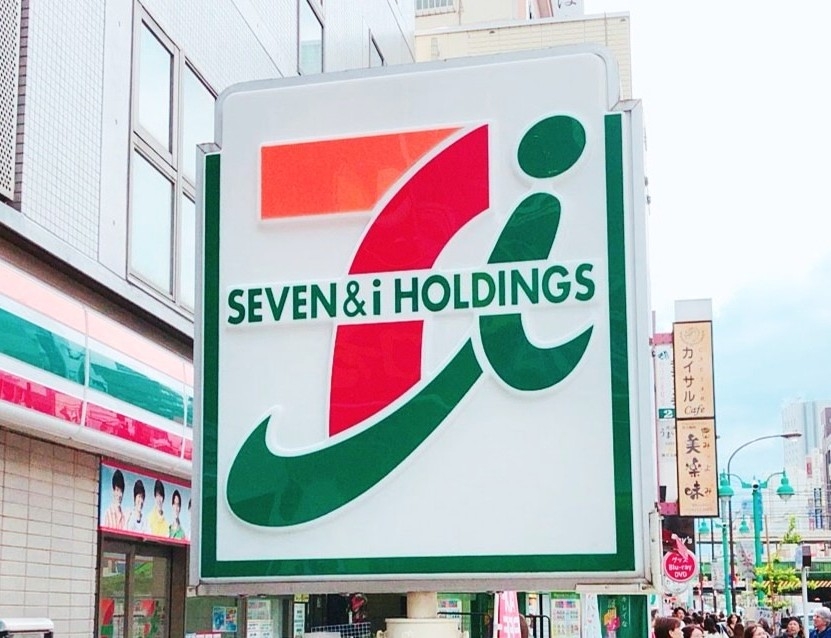 セブン＆アイ・ホールディングスの看板。背景に街並み。
