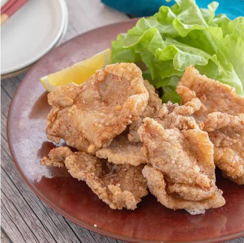 皿に盛られた揚げた肉とレタス、レモンのくし切りの食事イメージ。