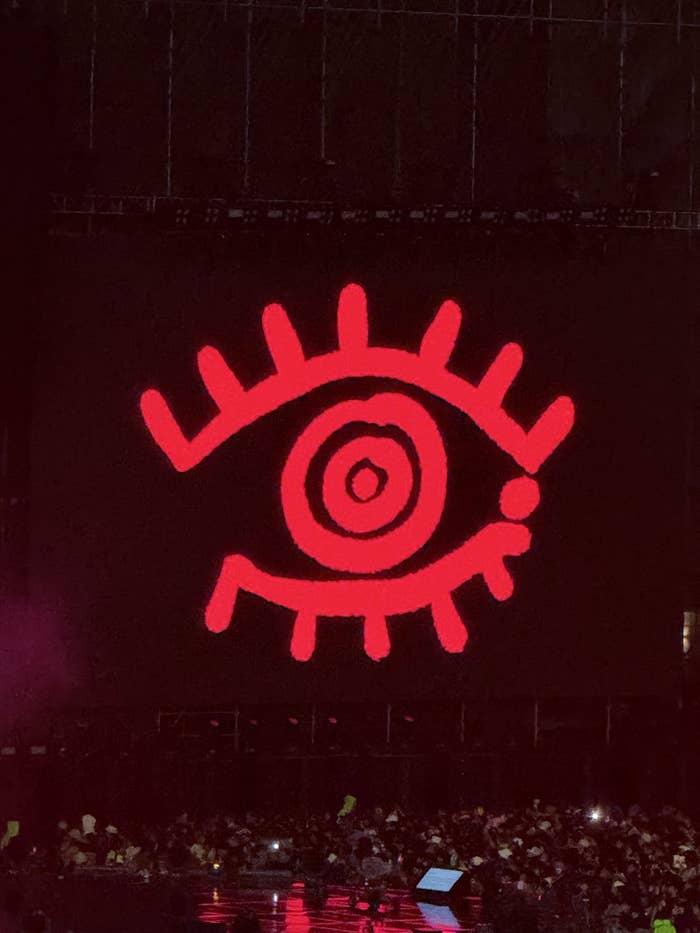 Ilustración de un ojo estilizado en rojo sobre el escenario de un concierto