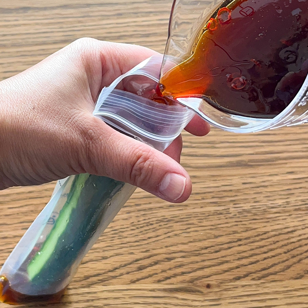 ジップ袋に液体が注がれている。袋の中にはキュウリが入っている。