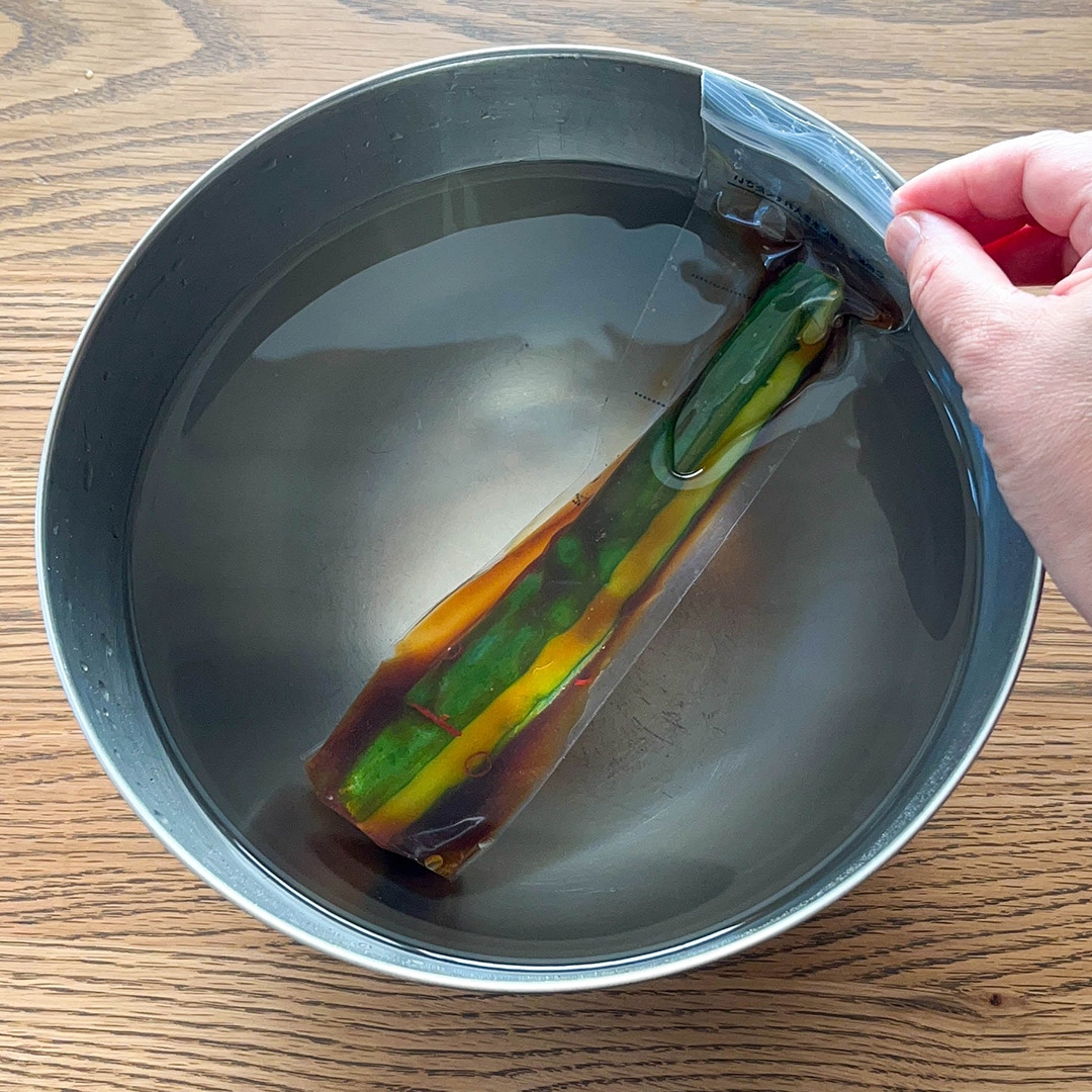 真空パック入り野菜が水の入ったボウルに部分的に浸かっている様子。