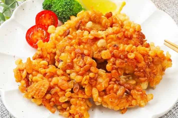 白い皿に盛られた天ぷら風の揚げ物。添えられたブロッコリー、トマト、レモンが見える。