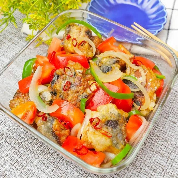 グリルされた魚とスライスしたトマト、ピーマン、玉ねぎが入った食欲をそそるガラスボウルの料理。