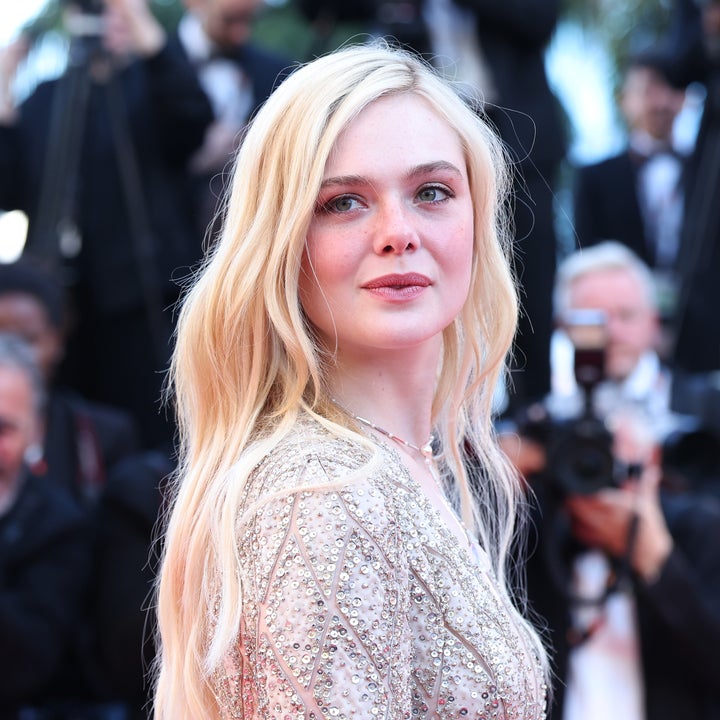 Actor on red carpet in beaded gown, surrounded by photographers