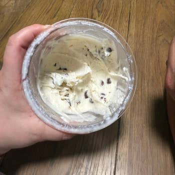 Person holding a tub of cocoa spot crystal pick connected a woody table