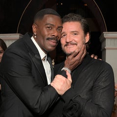 Two people in formal wear embrace and smile at an event