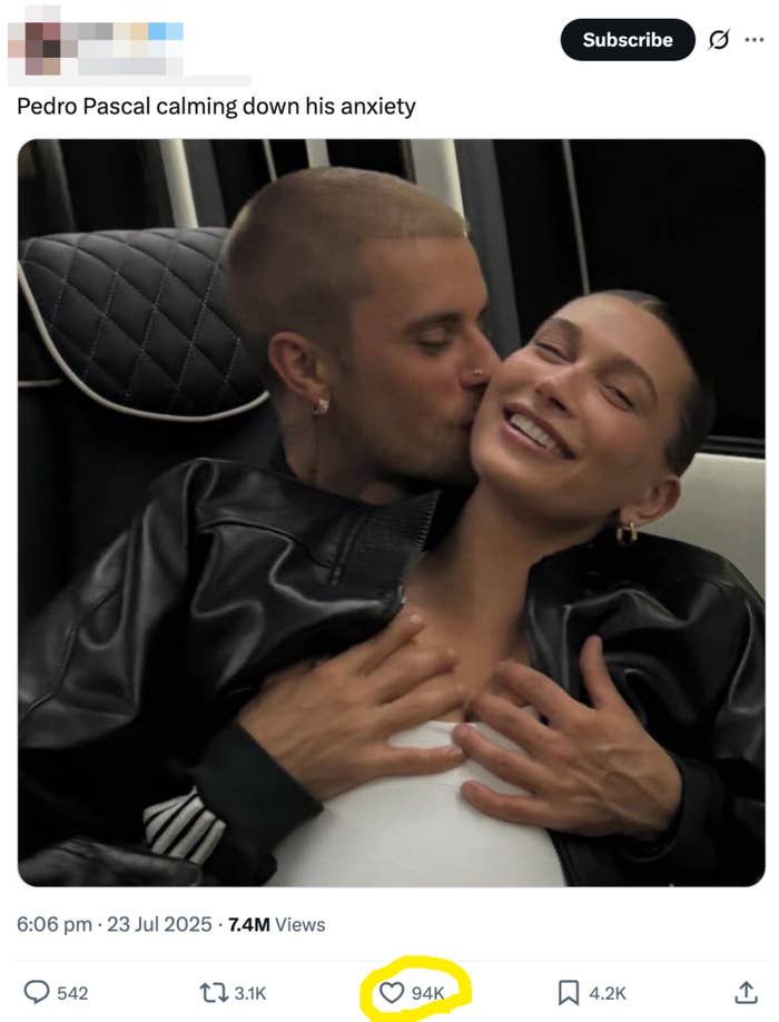 Two people sitting closely on a couch, one appears to be comfortable and smiling, while the other is affectionately kissing their cheek