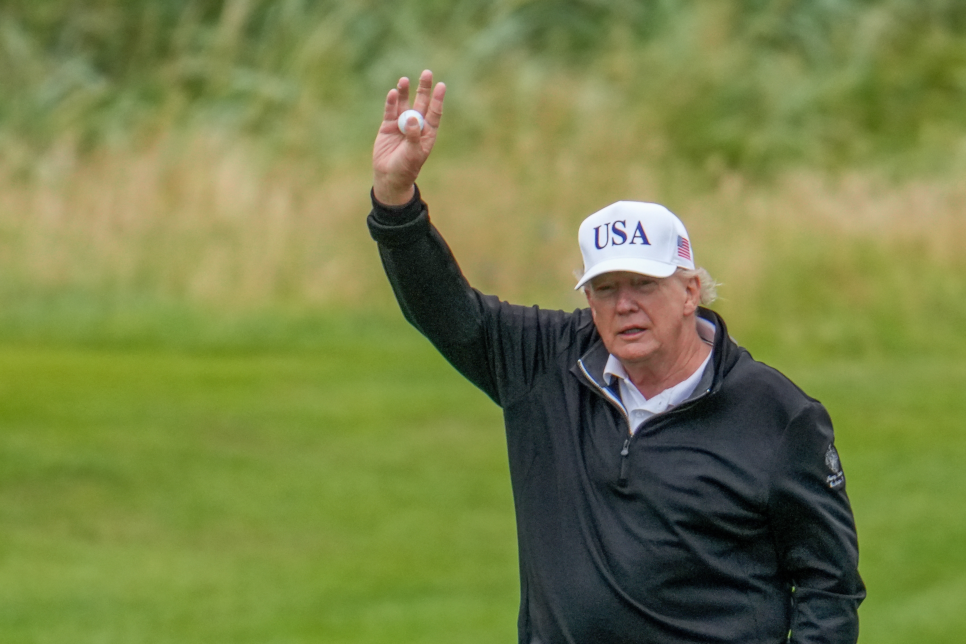 President Donald Trump holds up a golf ball as he plays a round of golf at Trump Turnberry golf course during his visit to the UK