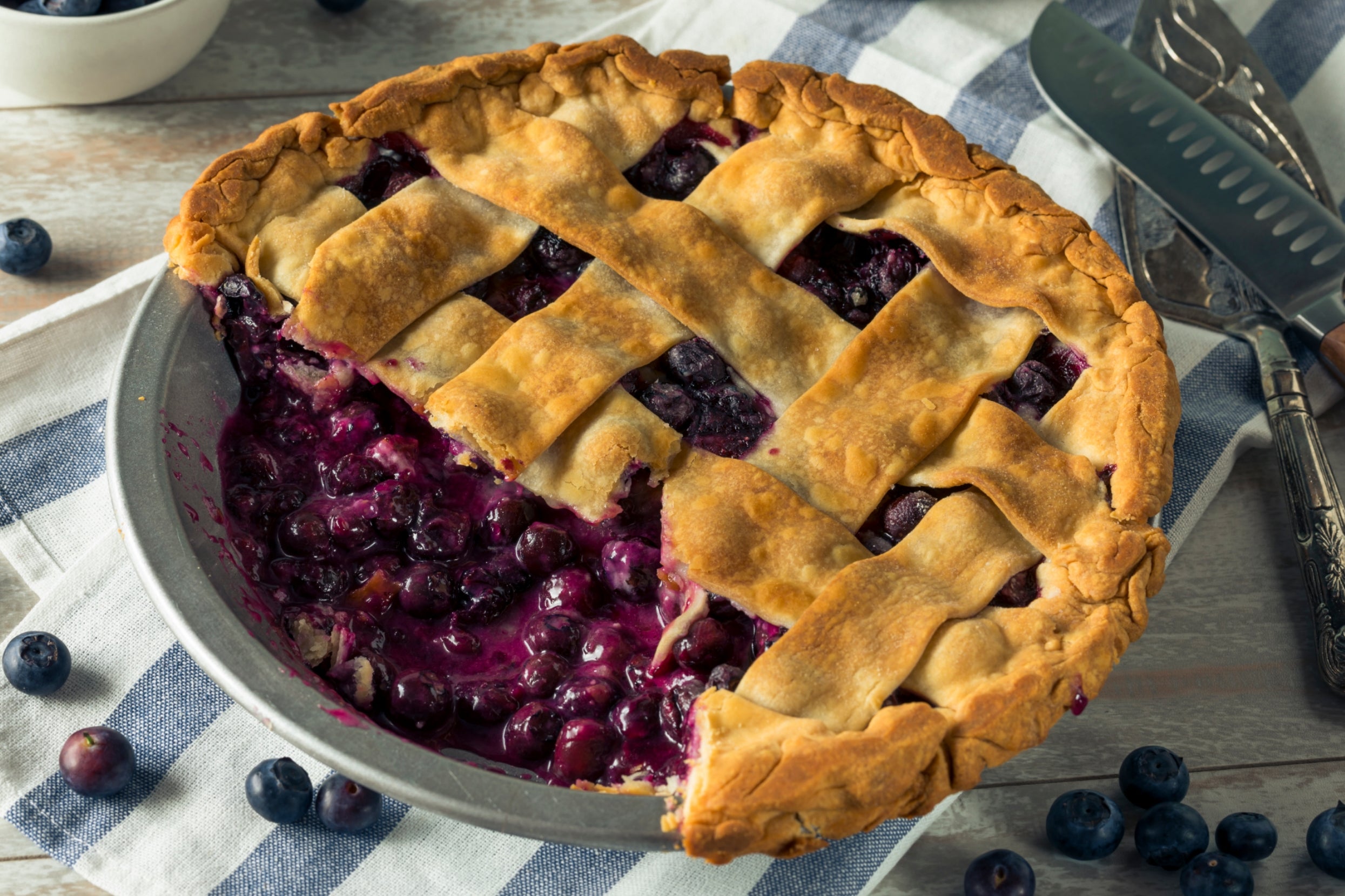 Blueberry pie with a lattice crust, missing one some slices, on a cloth