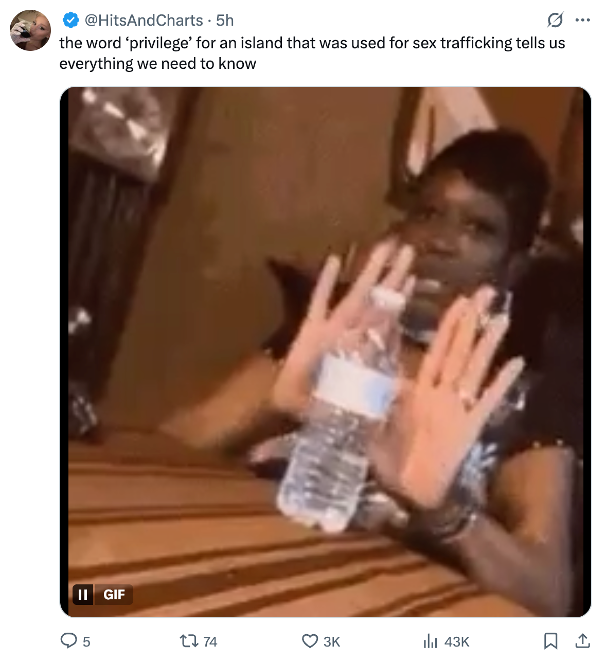 A person seated at a table is holding up their hands in a &quot;stop&quot; gesture while holding a water bottle