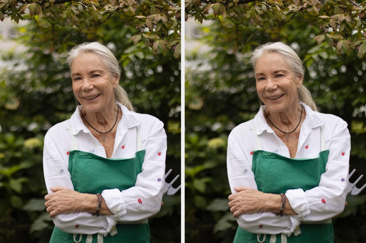 Person smiling in a garden, wearing a white shirt and green apron, with arms crossed. Background has leafy plants