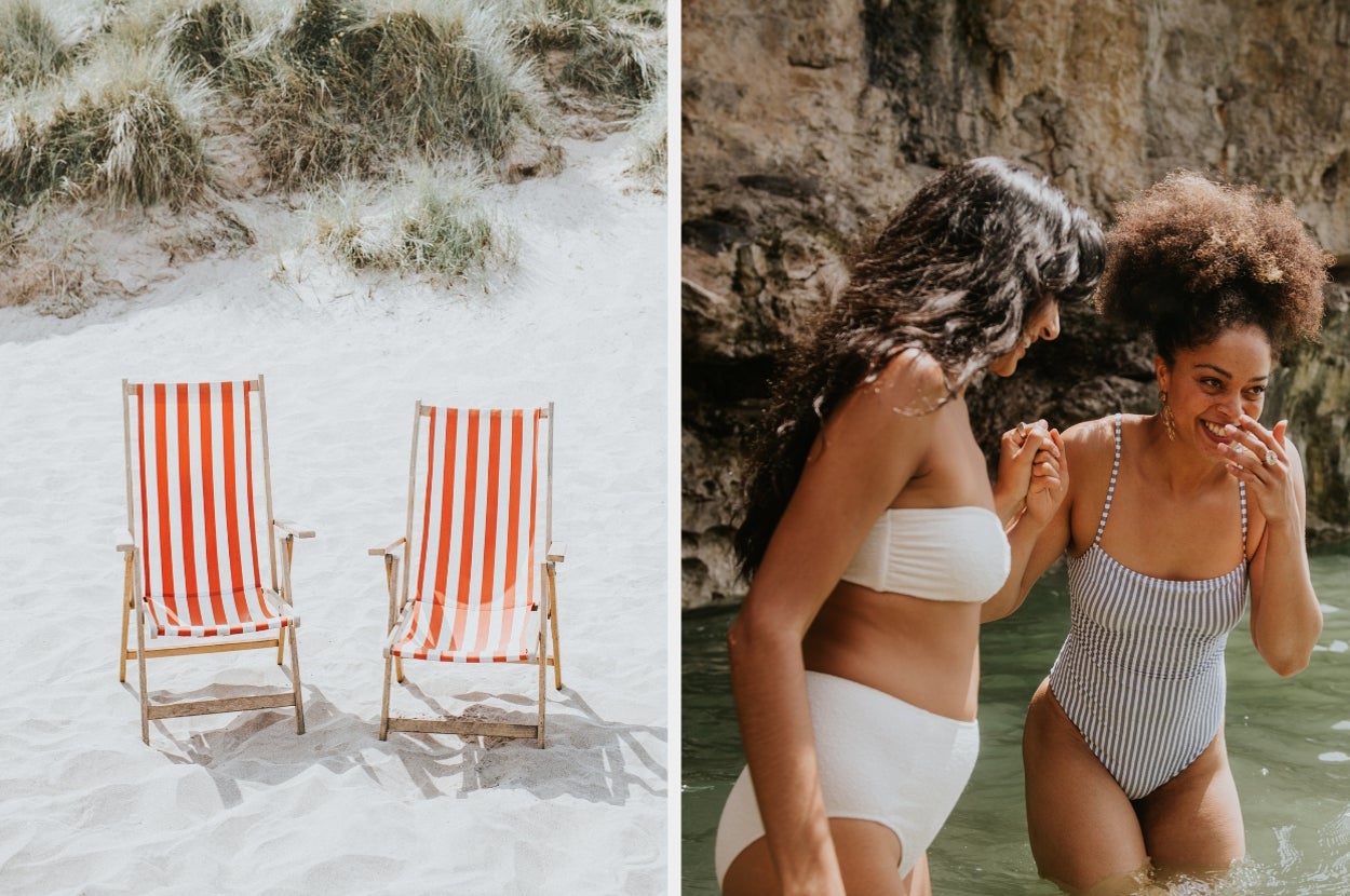 Two empty deck chairs on sandy beach; nearby, two women in swimsuits laugh and wade in shallow water near rocky shore