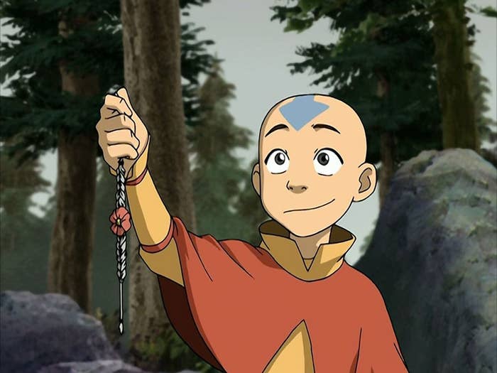 Personaje animado con túnica está sosteniendo un collar trenzado en un entorno bosque