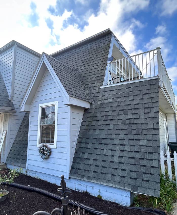Screenshot of a Reddit post asking why shingles are falling off a 2-year-old roof, with a photo of the roof and discussion thread below