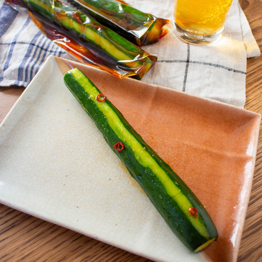 お皿に盛られた一本のキュウリに辛そうな調味料がかかっている。