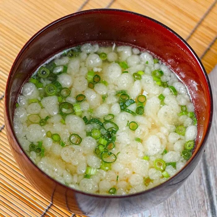 お椀に入った伝統的な日本の味噌汁。ネギと具が浮かび、温かく美味しそうな印象。