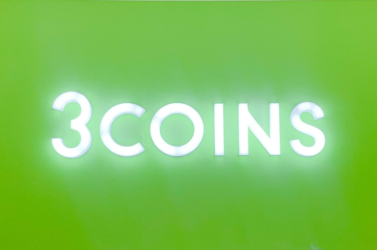 緑の背景に「3COINS」と書かれた看板があり、その下に割引のポスターが並んでいます。