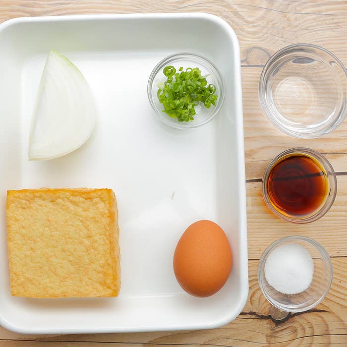 玉ねぎ、揚げ豆腐、卵、青ネギ、醤油、水、砂糖がトレイに配置されています。