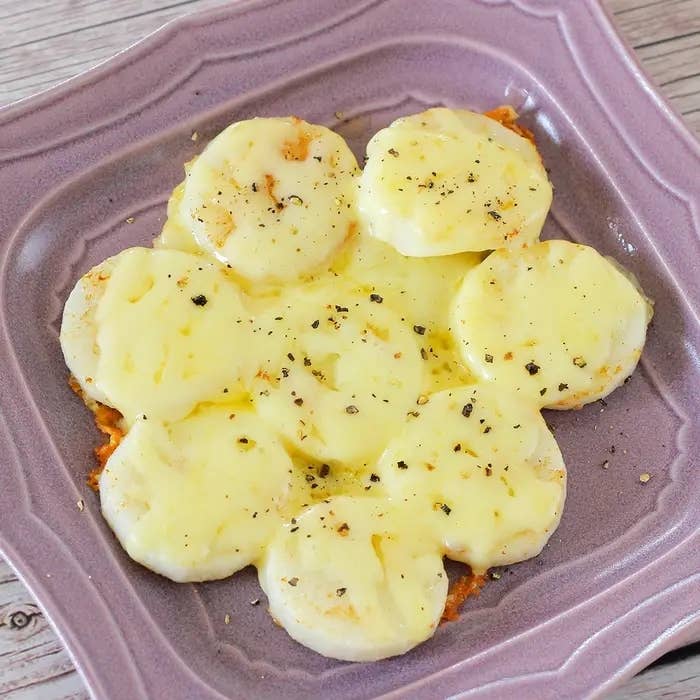 皿に盛られたチーズが乗ったじゃがいも。シンプルで美味しそうな料理。