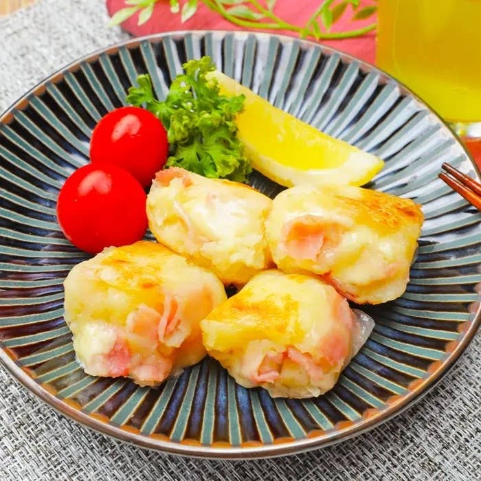 皿に盛られたトマト、レモン、と一緒にポテトとハムのグラタン。