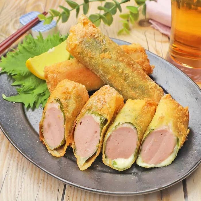 揚げた春巻きに包まれたソーセージが皿に盛られ、横には飲み物が置かれている。