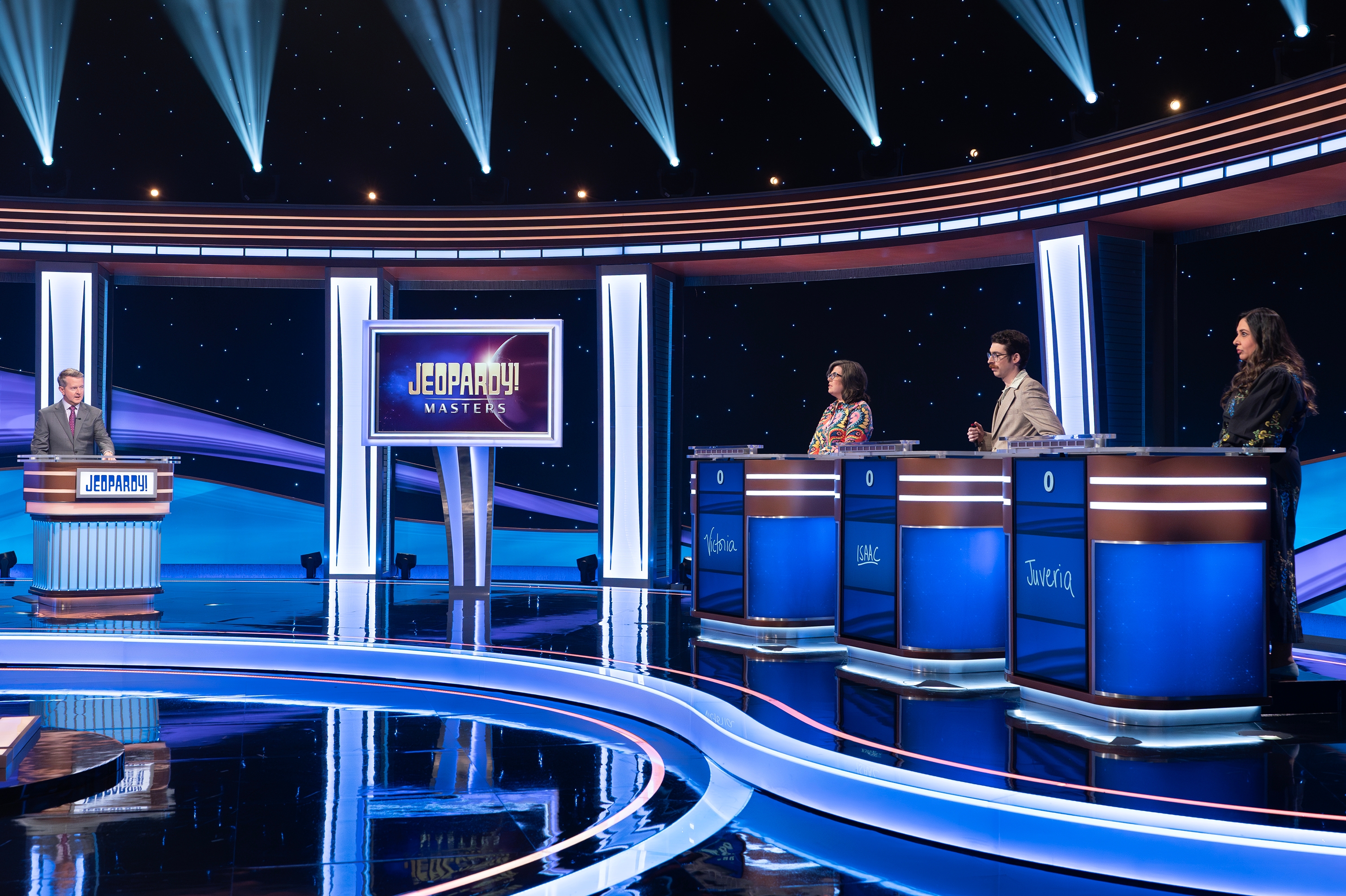 TV -spillprogrammet satt med fire deltakere bak podier og en vert på et podium. & quot; Jeopardy! Masters & quot; synlig på en skjerm