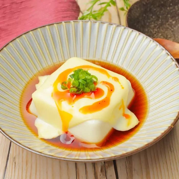 冷奴に醤油とラー油をかけた料理、上に刻んだネギがのっています。
