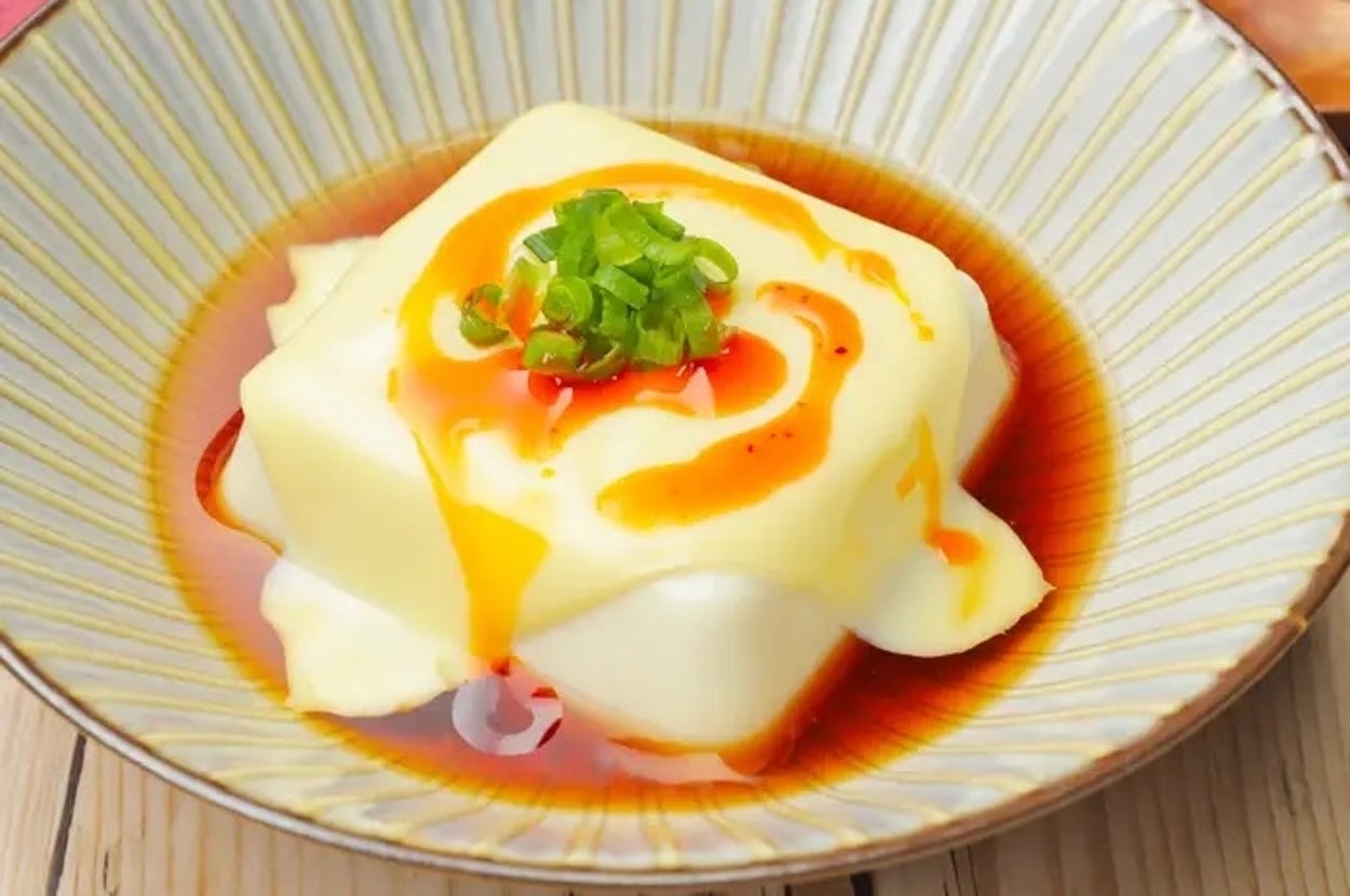 皿に盛られた冷奴に、醤油とラー油がかかり、細ネギがトッピングされています。