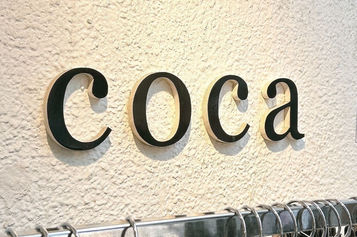 壁に「coca」と書かれた看板があり、その下に服が掛かっている。