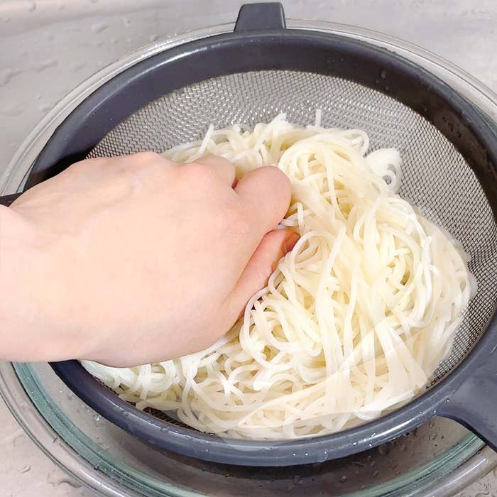 手で麺を押してる。