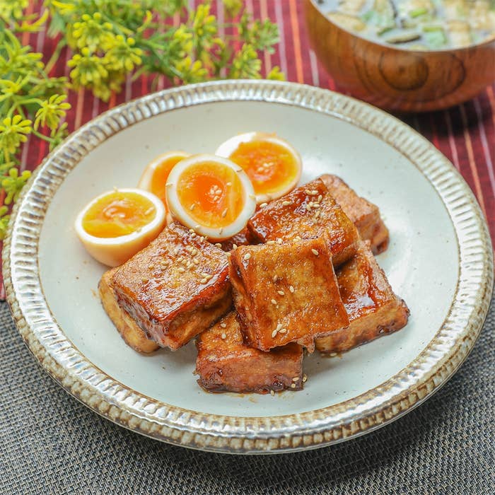 厚揚げとゆで卵の角煮風照り焼きが皿に盛られている。奥にはみそ汁が置かれている。