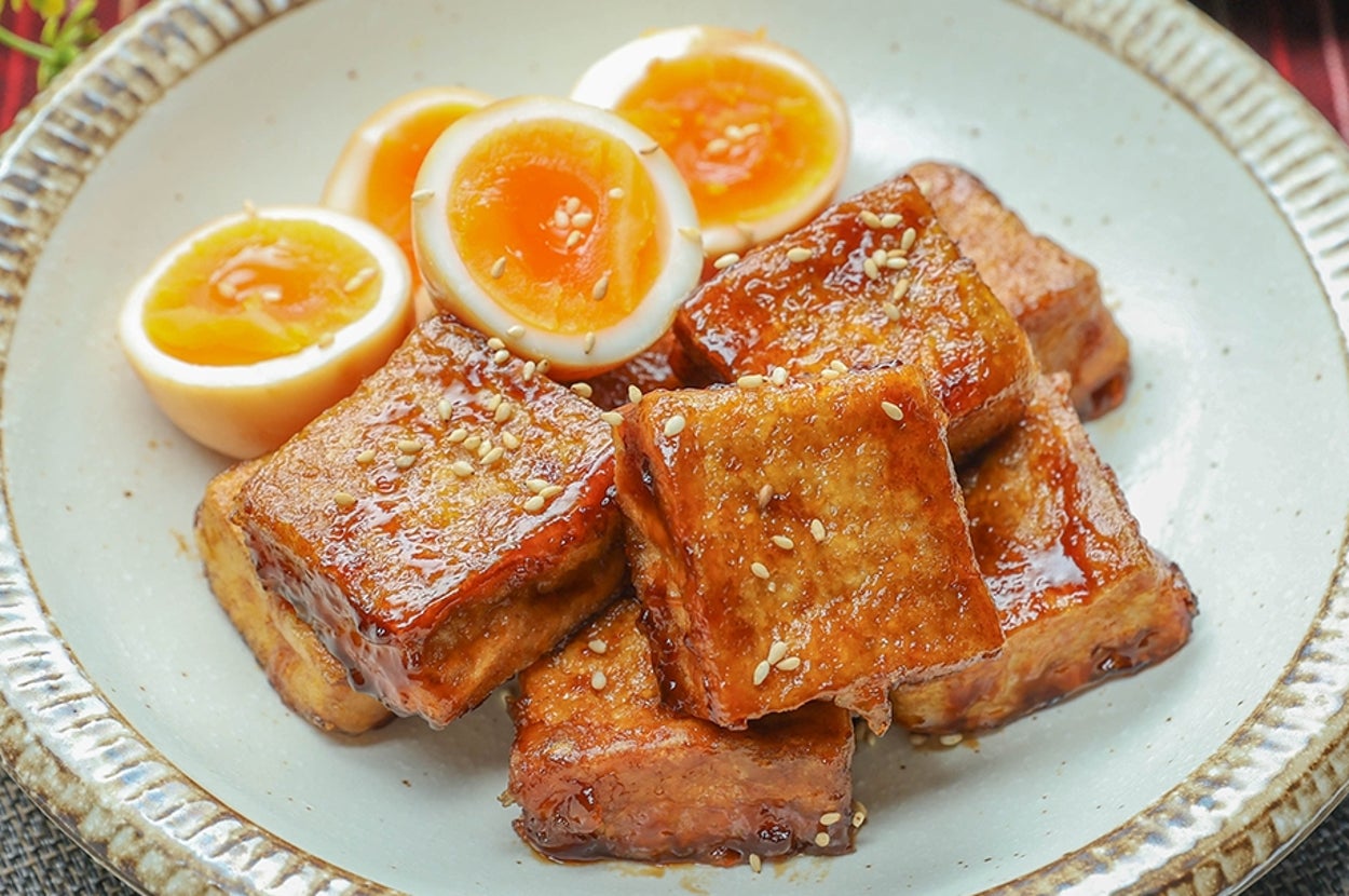 厚揚げとゆで卵の角煮風照り焼きが皿に盛られている。奥にはみそ汁が置かれている。