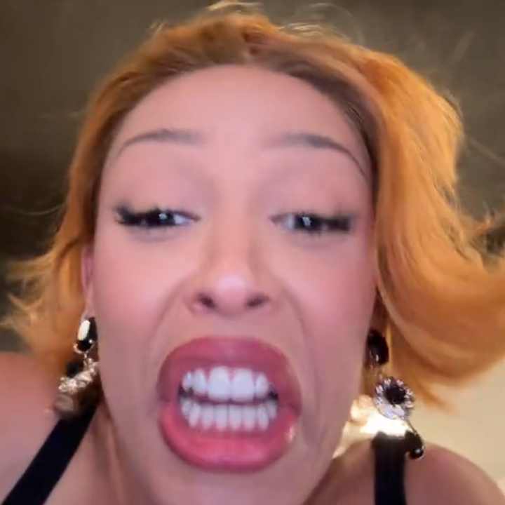 Person with short hair makes a playful exaggerated expression, wearing statement earrings