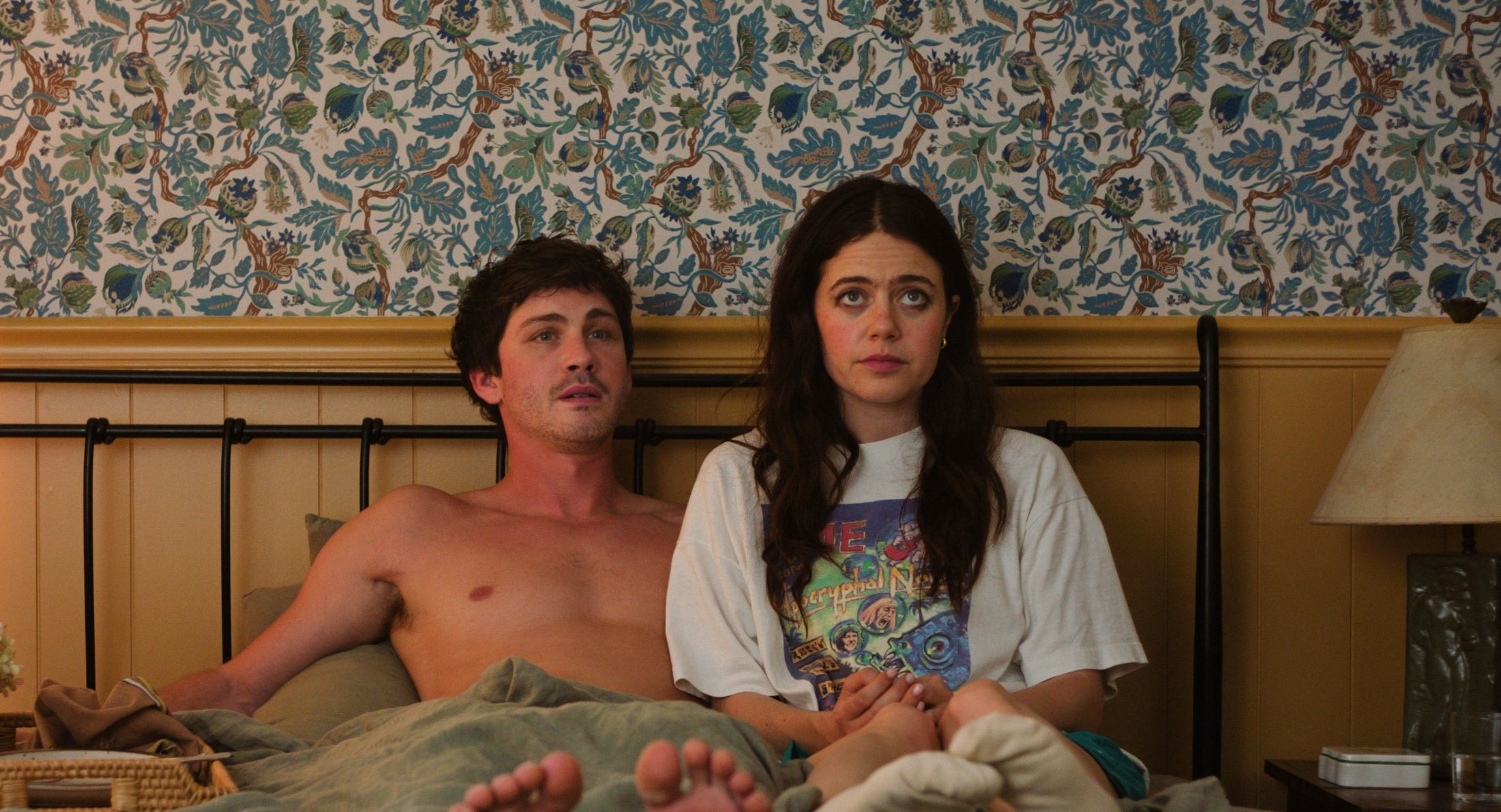 Molly Gordon and Logan Lerman lying in a bed together in a scene from "Oh, Hi"
