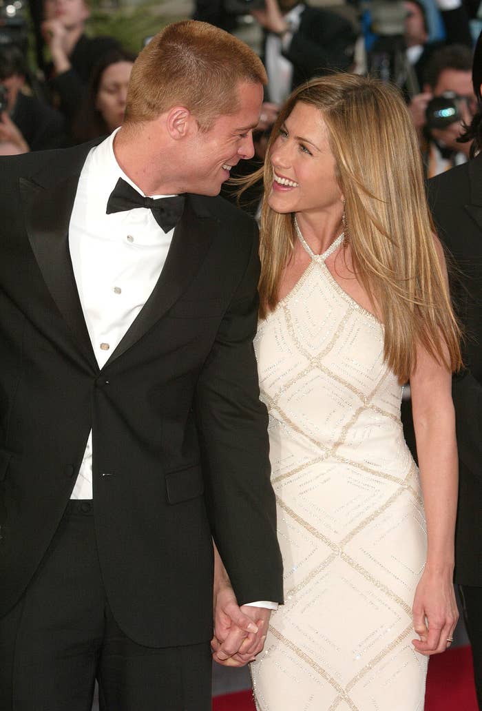 Brad Pitt and Jennifer Aniston smiling at each other on a red carpet