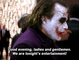 Side profile of a character in clown makeup and purple coat, delivering a dramatic line in a movie scene. Text reads: &quot;Good evening, ladies and gentlemen...&quot;