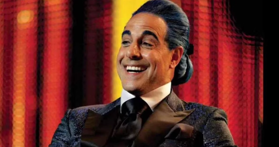 Man in a sparkling suit smiling broadly against a blurred, textured background