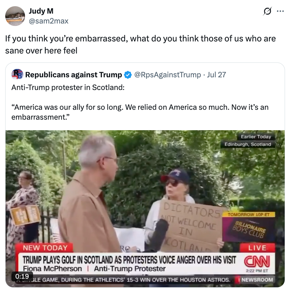 A protester in Scotland holds a sign reading “Dictators not welcome in Scotland” during a CNN report on anti-Trump protests at a golf event