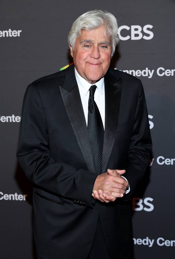 Person in a tuxedo smiles at an event, standing in front of a backdrop with CBS and Kennedy Center logos