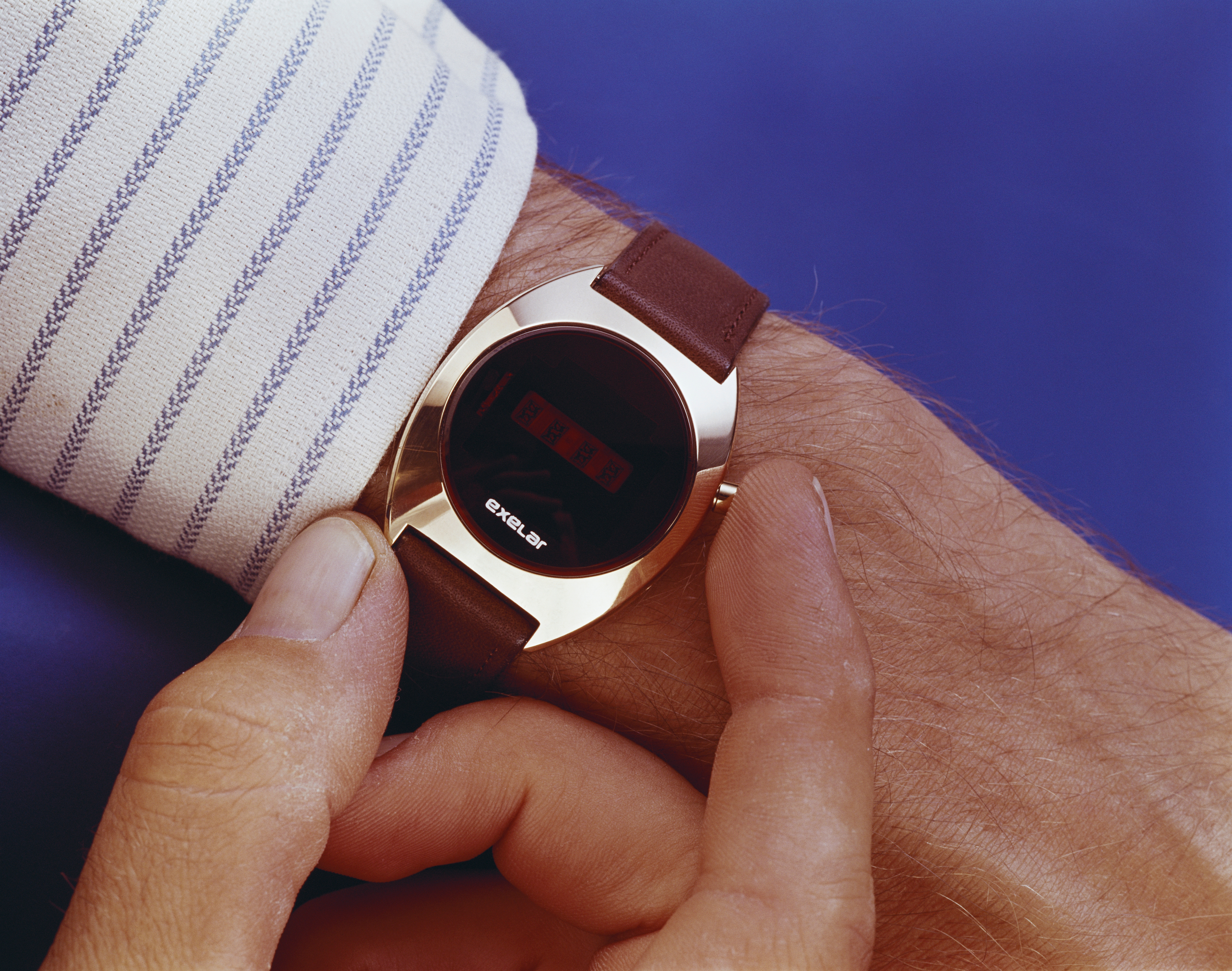 Person adjusting a digital watch with a sleek, futuristic design on their wrist