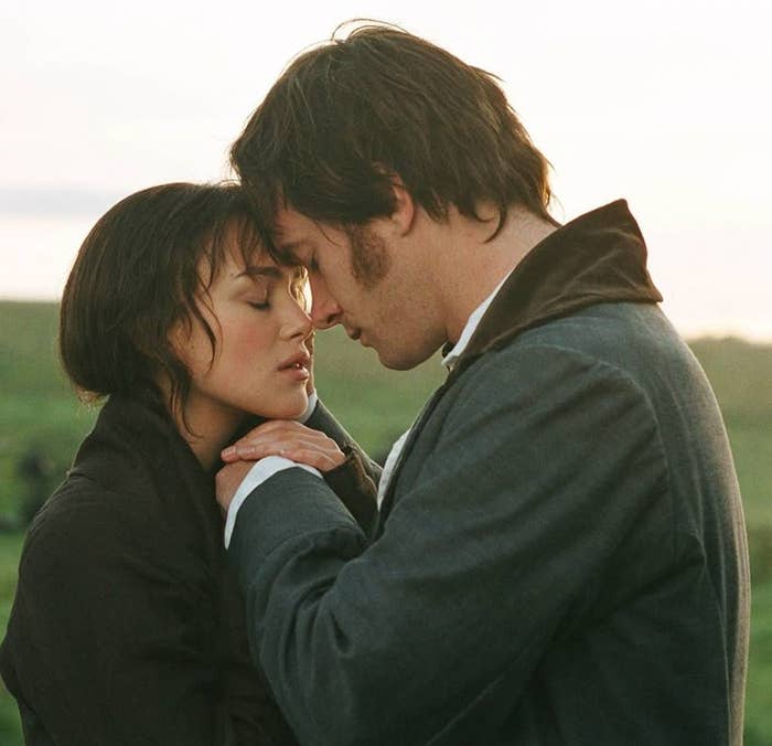 Pareja en un campo, con sus frentes juntas, en una escena romántica de época. Ambos lucen ropa clásica del siglo XIX