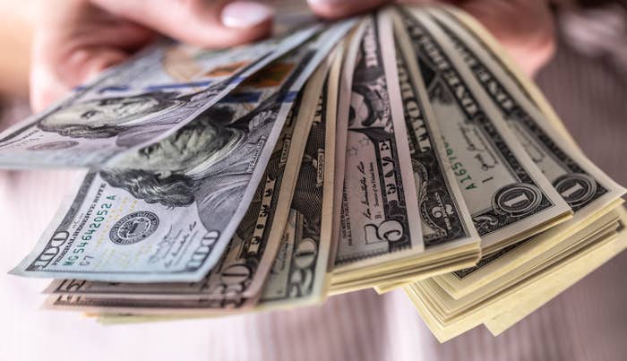 Hands holding a fan of U.S. dollar bills, showing various denominations