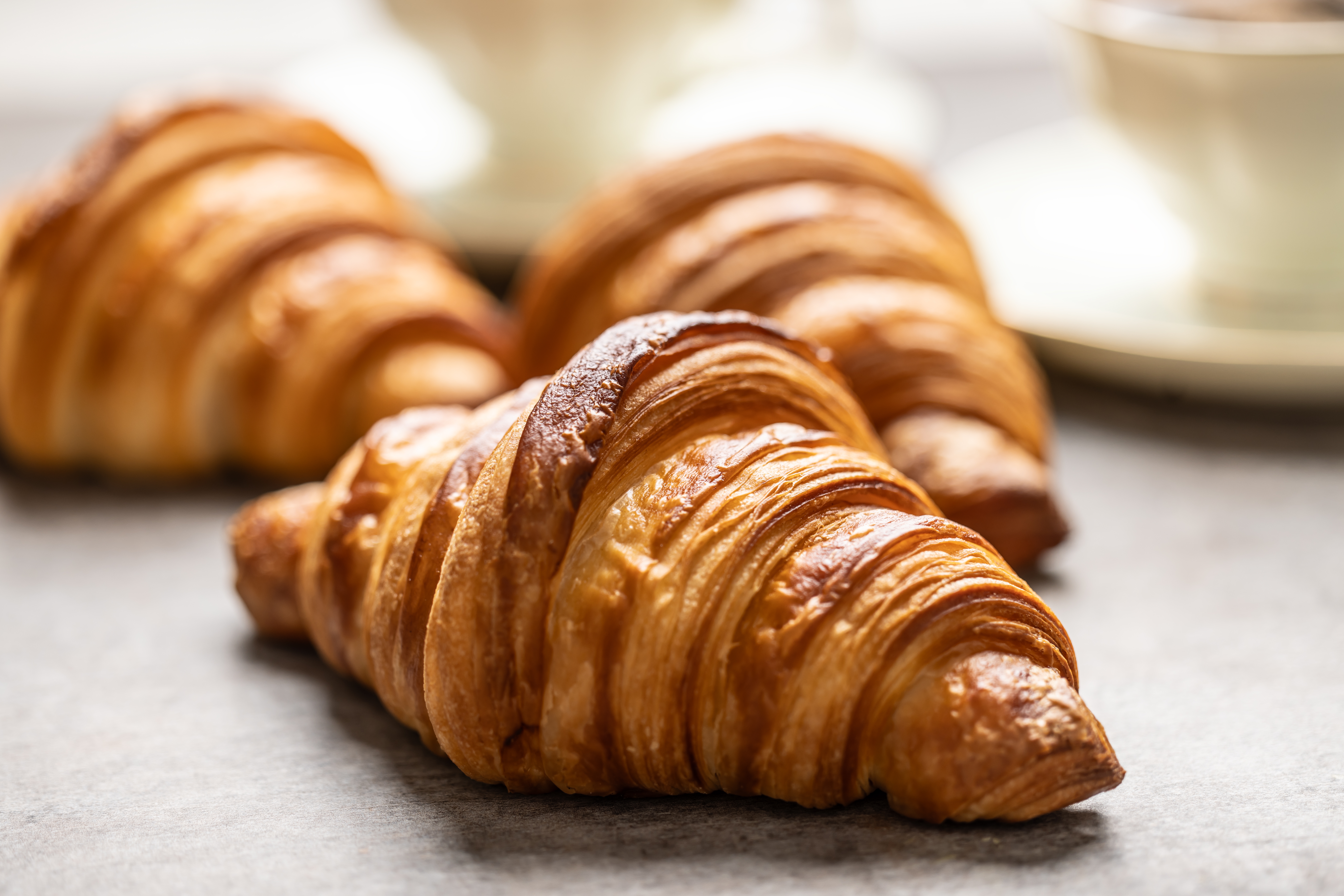 Close-up of three freshly baked croissants on a table, showing their flaky layers