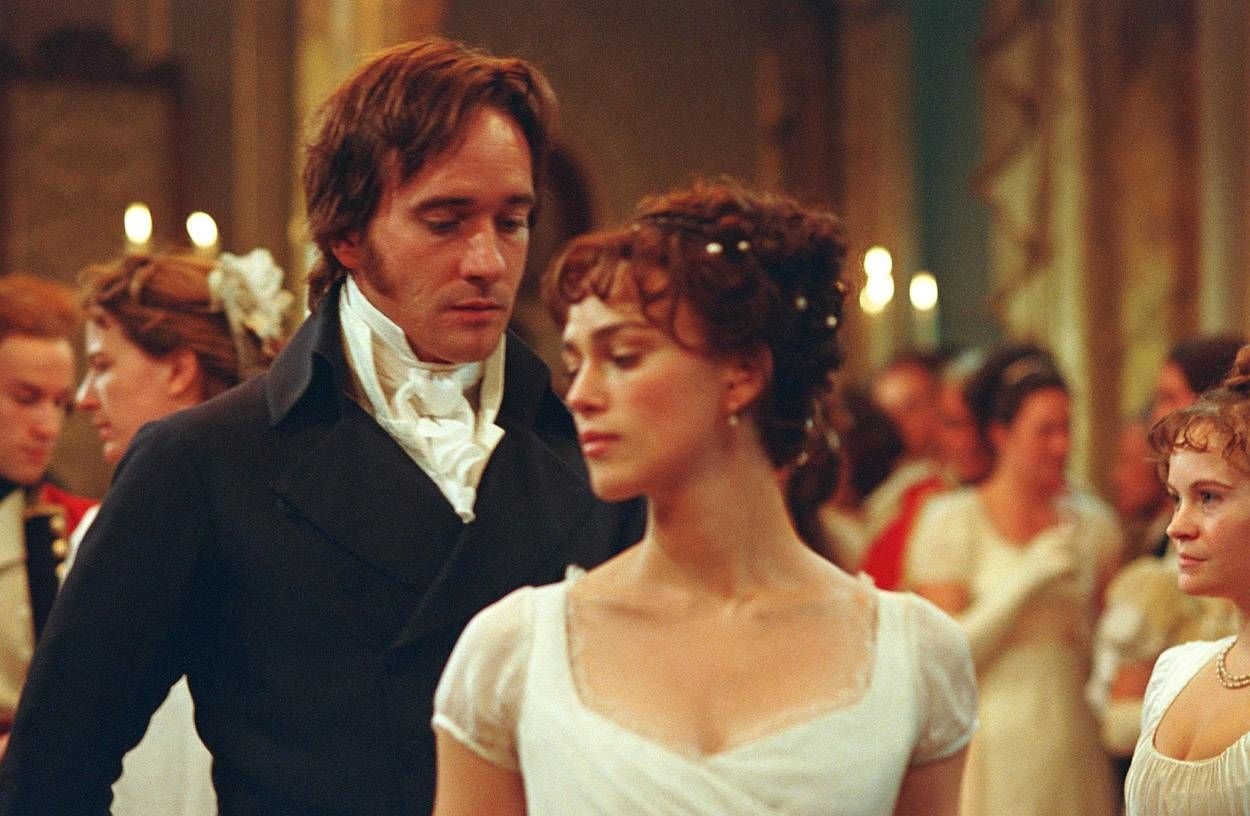 Escena de una película de época con un hombre y una mujer en trajes formales del siglo XIX en un salón de baile